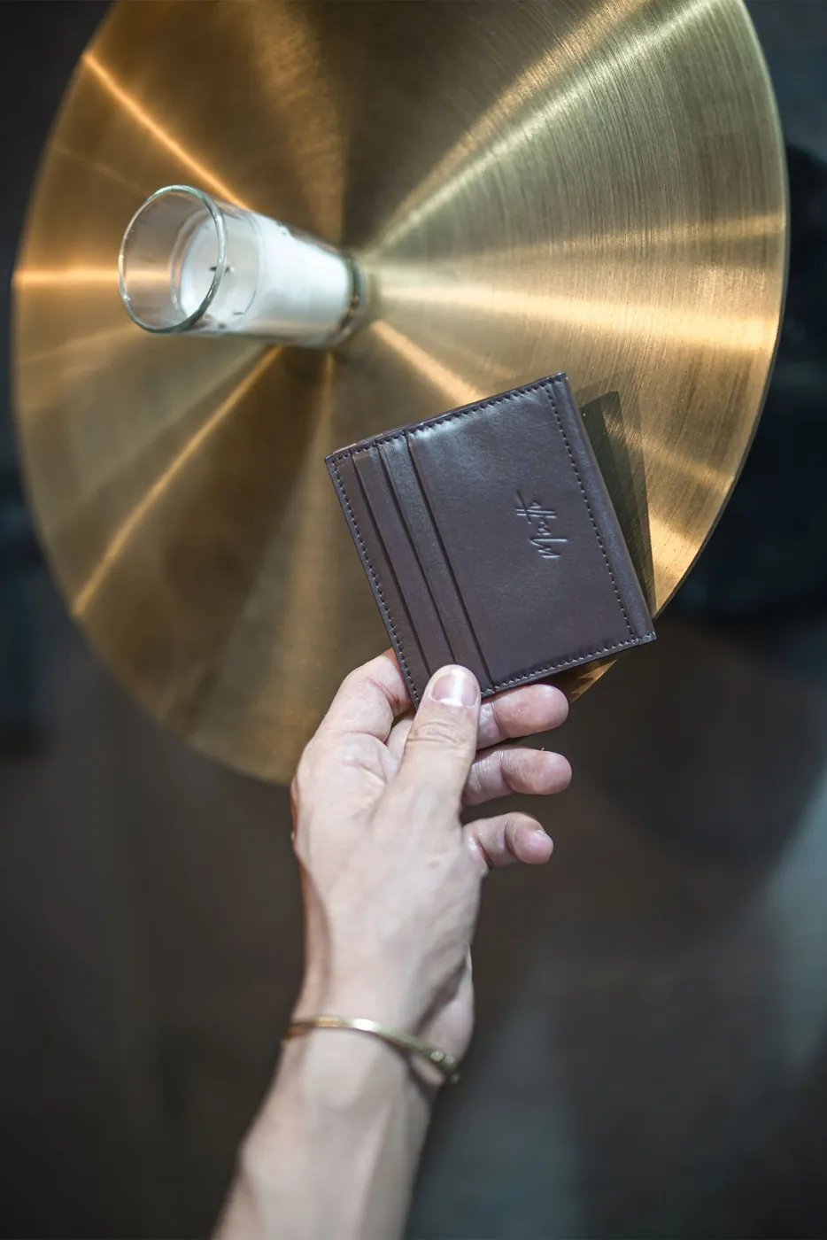Petit cuir noir tenu contre un disque de laiton doré